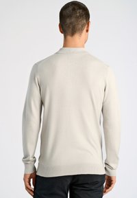 Helles graues Pullover mit einem gerippten Kragen und Bündchen. Besitzt eine glatte, weiche Textur und ein elegantes, tailliertes Design.