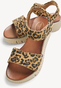 Sandales compensées pour femmes avec brides à imprimé léopard, brides ajustables à la cheville et aux orteils, semelle intérieure marron rembourrée et semelle extérieure beige rainurée.