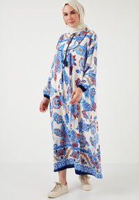 Rochie lungă, fluidă, de crem, cu modele florale albastre și roșii. Prezintă un decolteu rotund, mâneci lungi și accente bleumarin la tiv.
