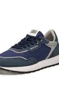 Baskets bleu marine en matériaux en daim et textile, avec un accent vert au talon et un logo blanc sur la languette. Semelle noire.