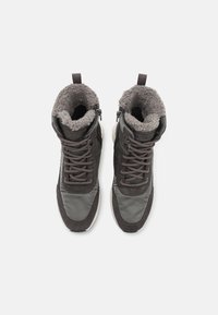Botas aisladas en gris y negro con un interior suave y peludo. Cuenta con un diseño de encaje, cremalleras en los laterales y un material exterior texturizado.