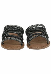 Sandales noires avec plusieurs brides ornées, présentant des textures tressées et perles, posées sur une semelle en suède synthétique beige.
