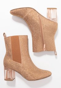 Botines nude con superficie texturizada adornados con pequeños rhinestones, que cuentan con un tacón bloque transparente, cierre lateral y paneles elásticos.