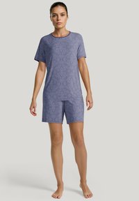 Paarse pyjamastel bestaande uit een T-shirt met korte mouwen en knielange shorts. De stof is textuur met een subtiel patroon doorheen.