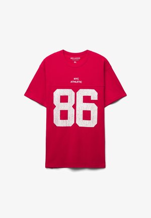 Maglietta rossa in cotone con vestibilità comoda, caratterizzata da una stampa bianca effetto usurato con "86" e "NYC ATHLETIC" sopra. Taglia XL. Maniche corte.