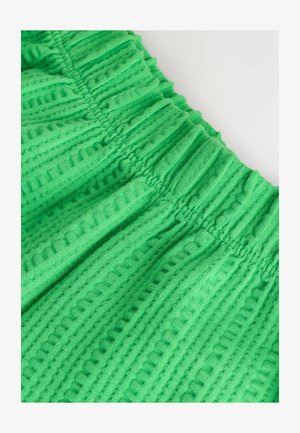 Zelena pamučna tkanina s teksturiranim uzorkom, s okomitim i vodoravnim rebrastim dizajnom te elastičnim pojasom.