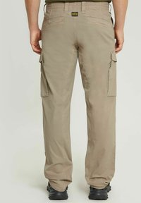 Pantaloni cargo beige realizzati in tessuto resistente, con due grandi tasche laterali, cuciture rinforzate e vestibilità rilassata. Etichetta nera G-Star sul retro.