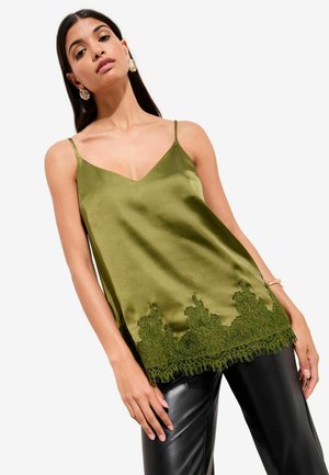 Satin olive green camisole with a V-neck and lace trim at the hem, paired with fitted black leather pants. Thin adjustable straps.