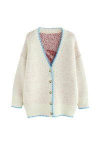 Džemper na kopčanje u boji kreme s crvenim sitnim točkicama; ima V-izrez, šest gumba i plavi nazubljeni rub duž izreza i donjeg ruba.