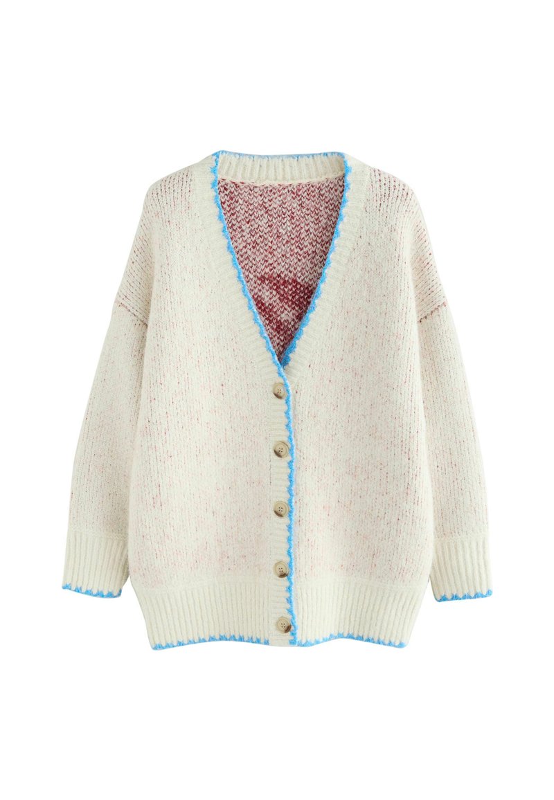 Džemper na kopčanje u boji kreme s crvenim sitnim točkicama; ima V-izrez, šest gumba i plavi nazubljeni rub duž izreza i donjeg ruba.