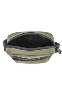 Borsa in silicone verde con superficie texturizzata. Chiusura con zip, ampio interno e un'area nera con branding. Progettata per un uso casual.