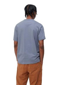 Camiseta gris de manga corta con un corte relajado, textura suave y dobladillo recto. Llevada con pantalones cargo beige que cuentan con bolsillos laterales.