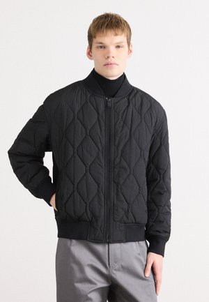 Black quilted bomber jacket with a stand-up collar, front zipper closure, ribbed cuffs, and hem, featuring a textured diamond pattern.