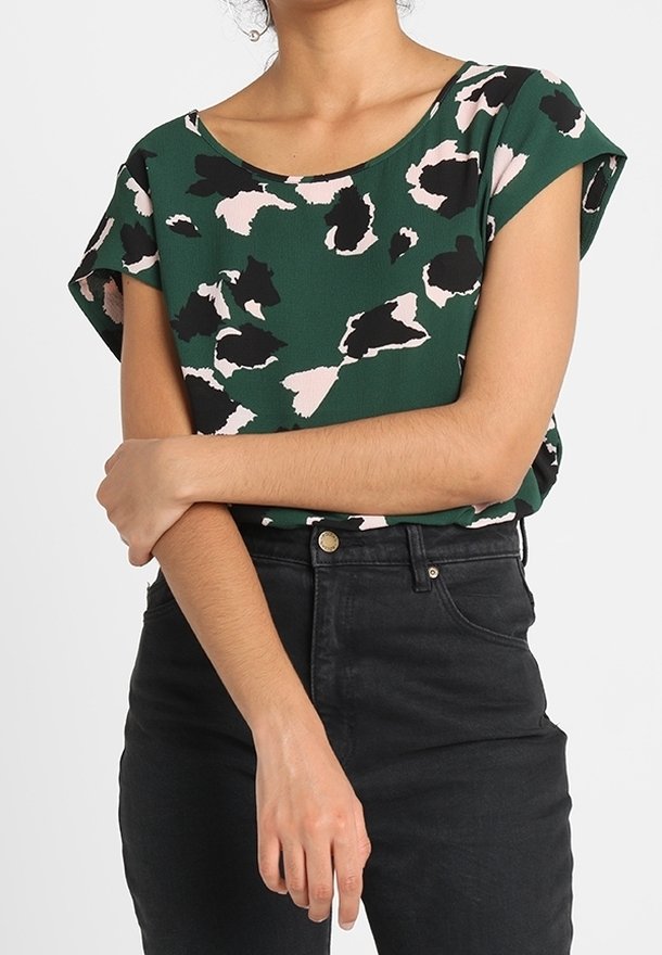 Haut à manches courtes vert avec des motifs abstraits noirs et rose pâle ; présente un col rond et une coupe décontractée. Associé à un jean noir taille haute.