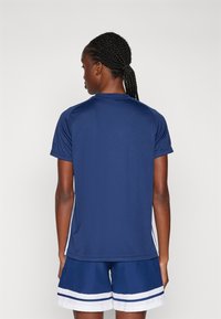Marineblauw sport T-shirt met korte mouwen en ronde hals, met contrasterende witte zijstrepen, gecombineerd met marineblauwe shorts met witte afwerking.
