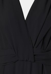 Robe noire portefeuille avec un décolleté en V profond et une taille froncée.