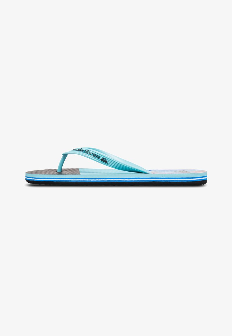 Chanclas de goma azules con plantilla texturizada, suela negra y ribete azul en contraste. Presentan un diseño de tiras minimalista y estampado de logo.