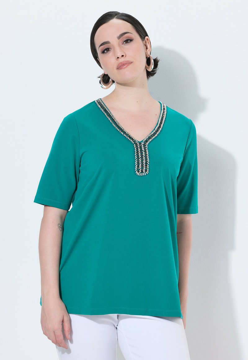 Top turchese a maniche corte con scollo a V, caratterizzato da cuciture decorative lungo il collo. Realizzato in un materiale liscio e leggero.