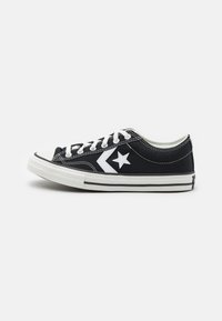 Sorte kanvas sneakers med hvite accenter, med en stjernelogo, klassisk gummitåhette, hvite snørebånd og stripete såledetaljer.