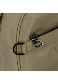Bolso de nailon caqui con un bolsillo con cremallera, textura suave y un tirador de cremallera de metal negro con un logo destacado y un anillo adjunto.