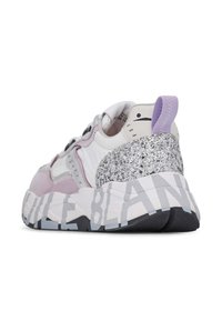 Chunky sneaker featuring white leather, light pink accents, a glittery silver heel, and bold black lettering on the sole. Rounded shape.