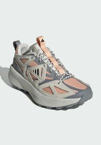 Grå och persika idrottssko med nätpaneler, integrerad snörning och en texturerad sula, med "LIGHTSTRIKE"-logotyp på sulan.