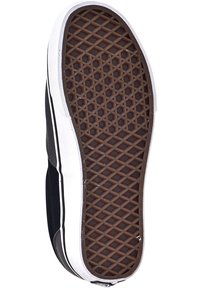 Chaussure en toile noire avec une semelle en caoutchouc blanche. La semelle présente un motif gaufré pour la traction et est bordée d'une bande blanche.