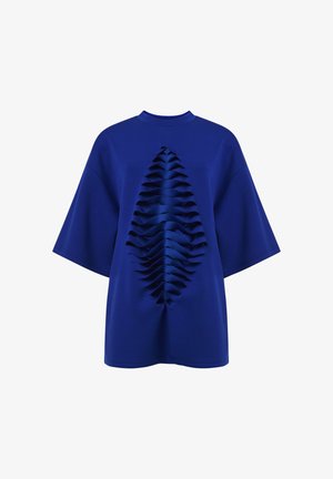 Camiseta azul de manga corta y corte holgado, con un frente texturizado que presenta detalles en capas con volantes, creando un contraste de diseño llamativo.