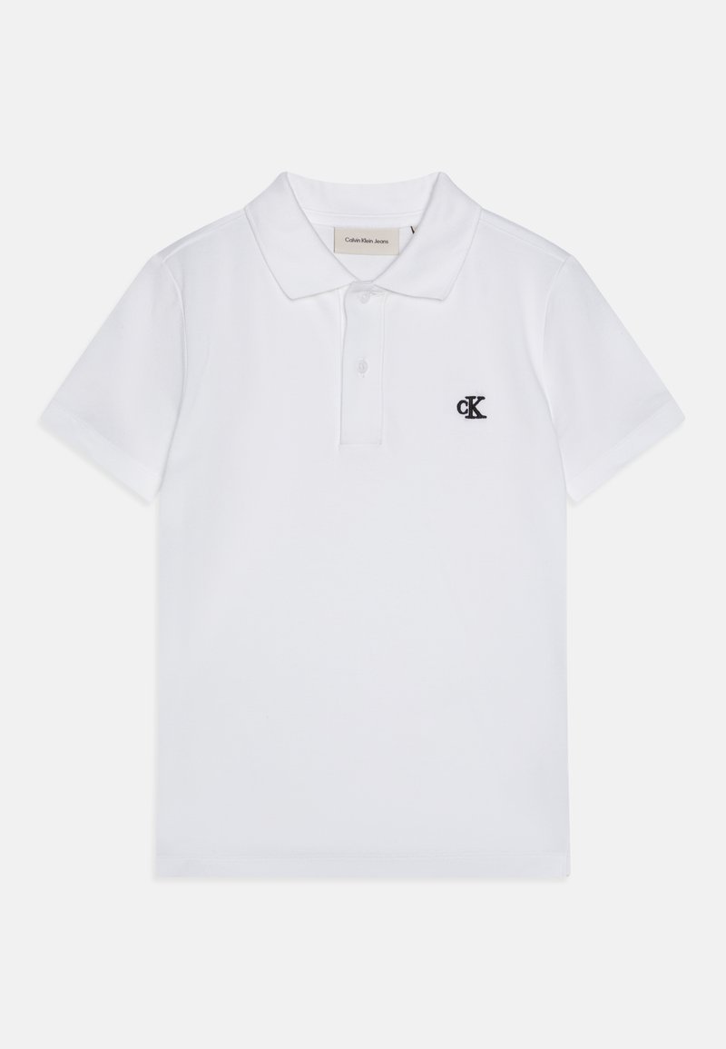 Bílá polo tričko vyrobené z bavlny, s klasickým límcem, krátkými rukávy a černě vyšitým logem "ck" na hrudi.