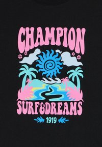 Musta T-särk, millel on värvikas graafika, kus on kujutatud päikest, pilvi, palme ja veeteed. Tekst "CHAMPION SURF & DREAMS 1919" roosa ja sinise värviga.