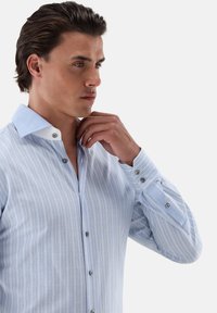 Hellblau gestreiftes Hemd mit weißem Kragen und Knopfleiste. Verfügt über kontrastierende Knöpfe und lange Ärmel mit Manschetten. Weicher Stoff.