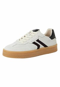 Hvite semskede sneakers med svarte detaljer, teksturert side og en gummisåle. Har runde lisser og en flat tunge-design.