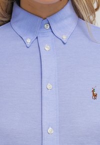 Himmelblaues Hemd mit Kragen aus strukturiertem Stoff, mit weißen Knöpfen und einem kleinen gestickten Polo-Spieler-Logo auf der linken Brust.