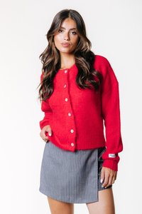 Rød strikket cardigan med frontknapper, lange ermer og ribbet kant. Kombinert med et stripete grått miniskjørt med sidehøft.