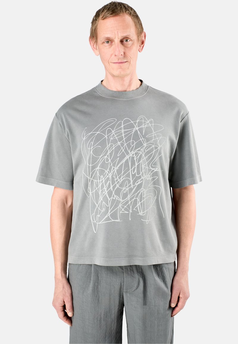 Grå bomulls t-shirt med korta ärmar, med en vit abstrakt linjedesign på framsidan och rundad halsringning.