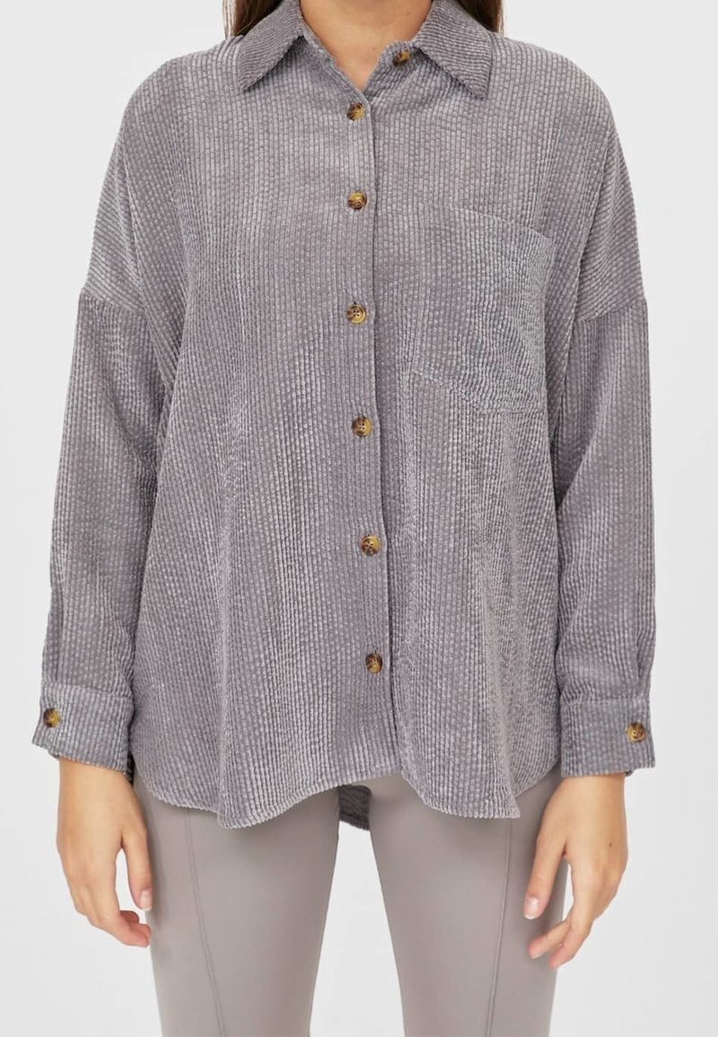Grå manchester-overskjorta med bröstficka och träknappar, med en avslappnad passform och långa ärmar med mudd detaljer.