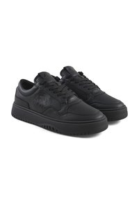 Zapatillas de cuero negro con un acabado suave, caja del dedo perforada, suela de goma gruesa y detalles laterales texturizados. Diseño con cordones.