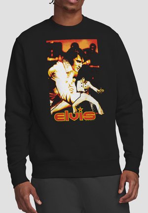 Black sweatshirt with two images of a male singer in white jumpsuit holding a microphone, text "elvis" in yellow and red below.