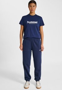 Granatowa bawełniana koszulka z białym logo "hummel", zestawiona z pasującymi granatowymi spodniami dresowymi z elastycznym pasem i mankietami.