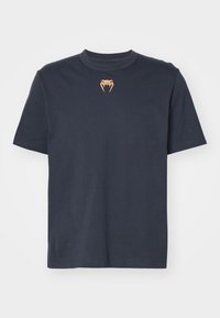 Granatowa koszulka z krótkim rękawem z małym pomarańczowym logo w kształcie kła węża, umieszczonym na środku poniżej okrągłego dekoltu.