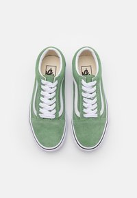 Gröna mockaskor med vita snören och detaljer. Rundad tå, vadderad krage och kontrasterande vita sidostriper. Gummisula.