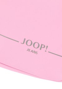 Sacchetto di tessuto rosa con il testo "JOOP! JEANS" in grigio. Texture liscia con un design minimalista e bordi curvi.
