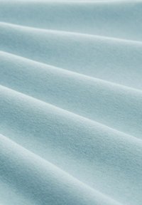 Light blue cotton fabric with a soft, smooth texture arranged in folds, showcasing subtle depth and a uniform, consistent color.