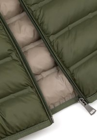 Ocieplana kurtka z ciemnozielonym zewnętrznym materiałem, jasnobeżową podszewką i podwójnymi zamkami błyskawicznymi. Posiada poziome pikowane sekcje i miękką fakturę.