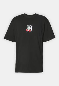 Camiseta de algodón negra con una letra "D" blanca bordada, adornada con cerezas rojas y hojas verdes, de mangas cortas y cuello redondo.