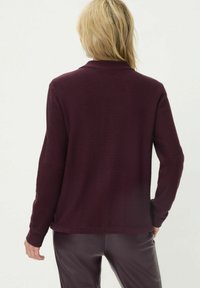 Bordeauxrode gebreide trui met lange mouwen en een kraag; heeft geribbelde manchetten en zoom, een gladde textuur en een losse pasvorm.