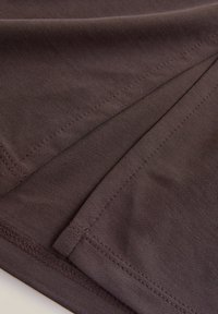 Tejido marrón con una textura suave, con detalles de costura en primer plano y bordes precisos, que resaltan la durabilidad y el diseño del material.