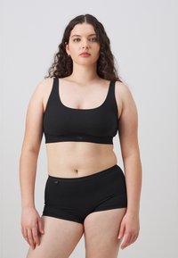 Svart bh och matchande boyshorts-set tillverkat av en mjuk, stretchig tyg. Har breda band och en åtsittande design för komfort.