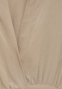 Tissu beige à texture lisse, doté d'un col en V, d'une taille froncée et de détails de couture discrets.