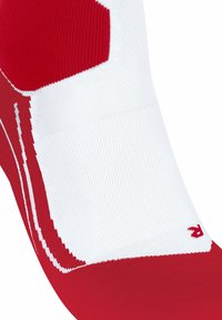 Rote und weiße Sportsocke mit gerippter Textur. Verfügt über eine nahtlose Spitze, gepolstertes Fußbett und ein auffälliges Logo im unteren Bereich.